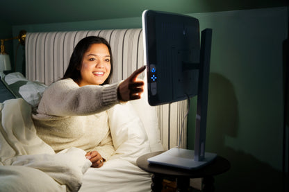 Woman in bed turning on the Day-Light Elite for a morning light therapy session
