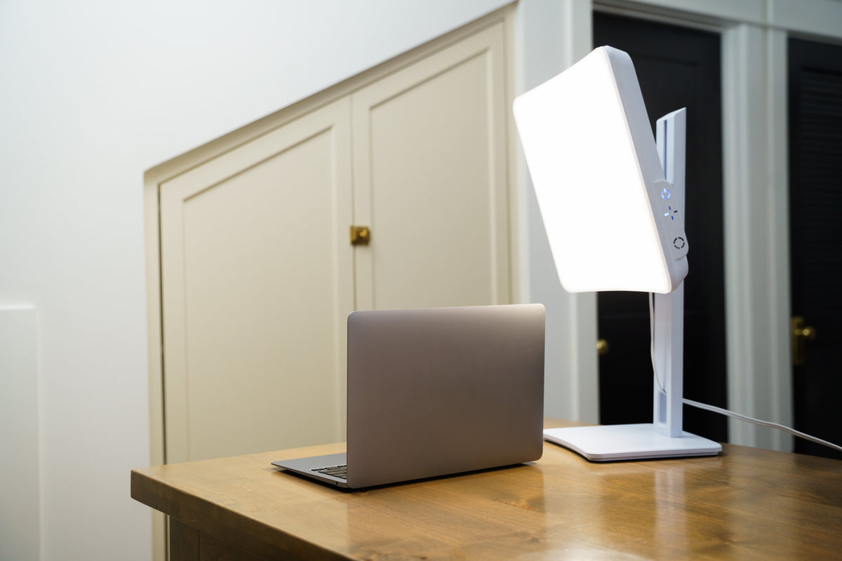 Day-Light Elite light therapy lamp beside a laptop on a wooden desk