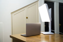 Day-Light Elite light therapy lamp beside a laptop on a wooden desk