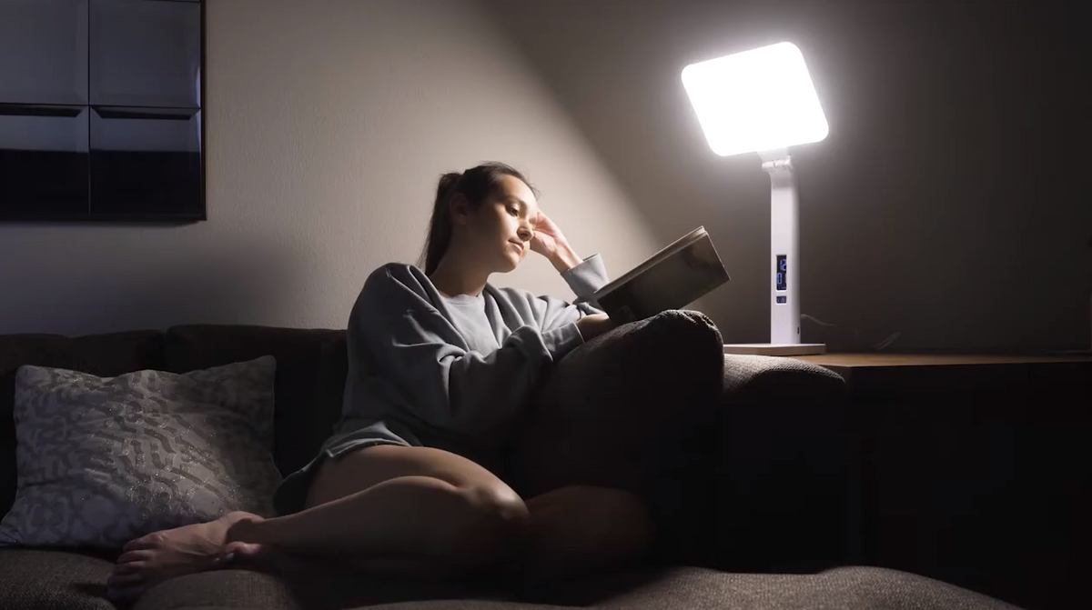 Person enjoying warm morning light from the TheraLite Aura Qi